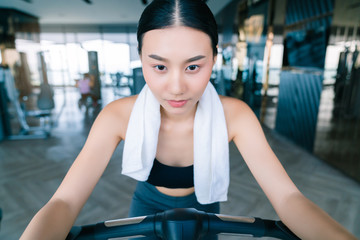 Fototapeta na wymiar strong and firm asian woman sport wear relax on bicycle hand hold white napkin fitness background