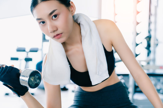 Beautiful fit Asian woman doing exercise with Dumbbell Bicep Curls healthy ideas concept in gym fitness