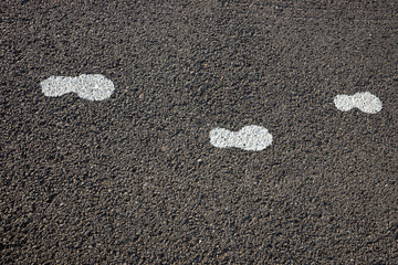 White footstep symbol painted on the asphalt ground floor to guide the tourist for the position
