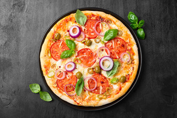  Italian pizza with melted mozzarella cheese green olives and tomato garnished with fresh vegetables and basil leaves.