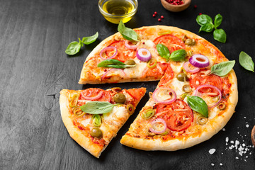  Italian pizza with melted mozzarella cheese green olives and tomato garnished with fresh vegetables and basil leaves.