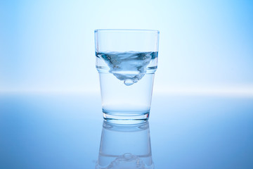 Drinking water in a glass with blue background
