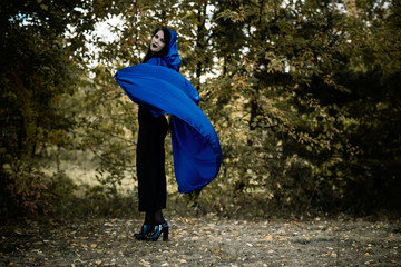 Halloween time, witchcraft, modern gothic girl in blue cloak celebrate. Good ideas for photoshots, cosplay 