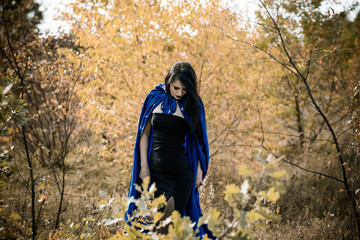 Halloween time, witchcraft, modern gothic girl in blue cloak celebrate. Good ideas for photoshots, cosplay 