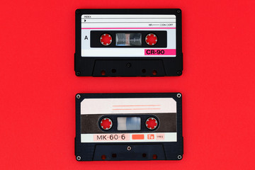 Two old audio cassettes on a bright red background. Top view, old technology concept