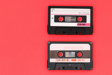 Two old audio cassettes on a bright red background. Top view, old technology concept