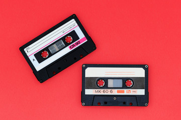 Two old audio cassettes on a bright red background. Top view, old technology concept