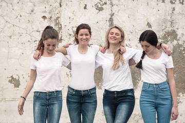 Group of diverse girls in tshirts and jeans over street wall