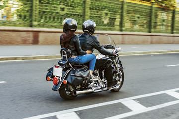a man drives a girl on his black motorcycle