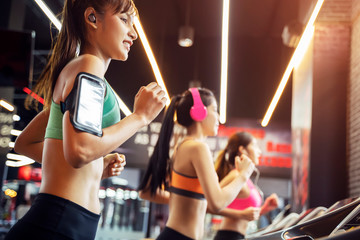Group of young sport women running with happiness together at gym. Listening to music with wireless earphone.