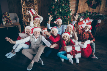 Portrait of nice lovely cheerful big full family brother sister couples wearing cap hat headwear sitting on floor holding in hands gifts waving hi hello tradition loft industrial style interior house