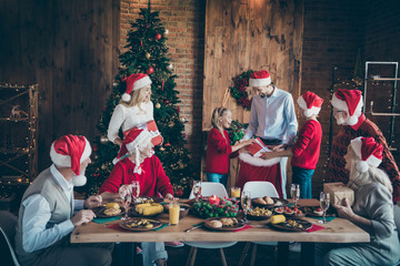 Photo of full harmony family gathering dinner table sharing x-mas presents getting out large santa pack red giftbox in decorated living room with x-mas tree indoors