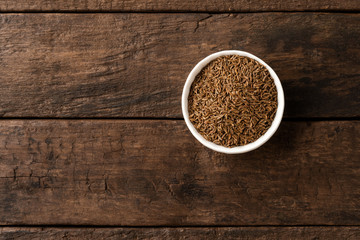 Caraway in bowl on retro wooden background. Top view