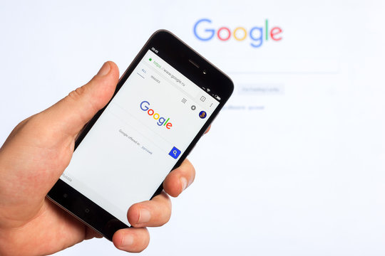 Adygea, Russia - January 4, 2018: the home page of popular web site the American search engine Google on the screen of the Chinese Xiaomi smartphone in male hand