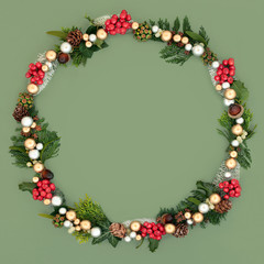 Christmas wreath with gold and silver baubles with a variety of winter flora and fauna on green background with copy space.