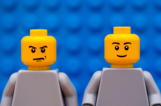 Tambov, Russian Federation - July 24, 2016 Two Lego minifigures - one strict and one smiling. Blue background. Studio shot.