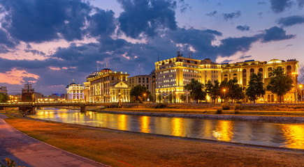 Fototapeta na wymiar Downtown of the Skopje at sunset with city lights reflected on Vardar river. North Macedonia.
