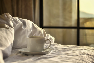 White coffee cup on bed in the morning. 