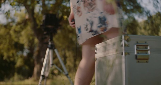 young woman setting up large format camera in nature