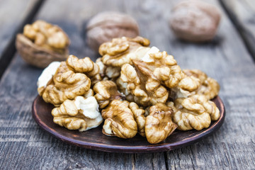 Walnut kernels lie in a bowl on a rustic old wooden table. Fresh walnuts.