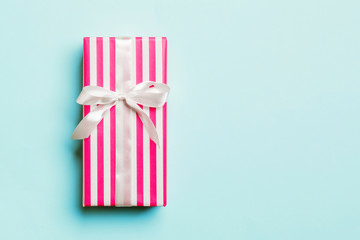 wrapped Christmas or other holiday handmade present in paper with white ribbon on blue background....