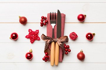 Naklejka na ściany i meble Top view of holiday set of fork and knife on wooden background. Christmas decorations and toys with copy space. New Year Eve concept