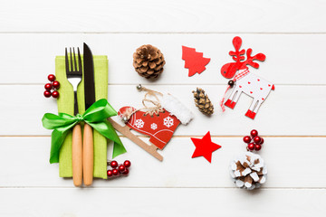 Top view of fork and knife on napkin on wooden background. Different christmas decorations and toys. Close up of New Year dinner concept