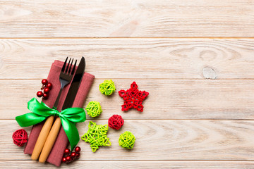 Top view of holiday set of fork and knife on wooden background. Christmas decorations and toys with copy space. New Year Eve concept