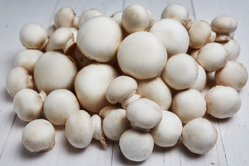 Fototapeta na wymiar Champignon mushrooms on a white wooden background