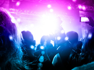 Concert hall crowded with people in front of a stage lit for the gig.