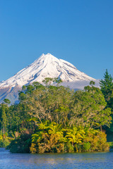 Fototapeta premium Snow covered Mount Taranaki viewed from Lake Mangamahoe. Also known as Mount Egmont this dormant volcano is located in the Taranaki District of the North Island of New Zealand.