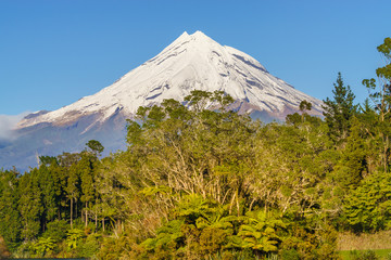 Fototapeta premium Snow covered Mount Taranaki viewed from Lake Mangamahoe. Also known as Mount Egmont this dormant volcano is located in the Taranaki District of the North Island of New Zealand.