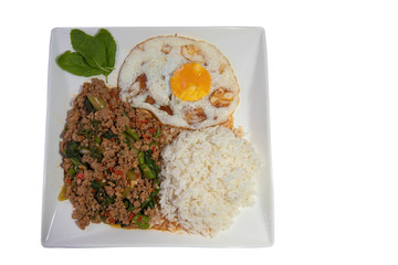 Thai food stir-fried pork spicy and basil served with rice and fried egg and tomato cucumber carved white plate top view isolated on white background