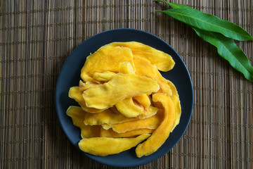 Dehydrated Mango or Dried Mango slices in plate on wooden table with Mango leaf        
