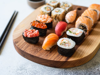 Variety of sushi, rolls and gunkan served on a wood board. Shrimp, unagi, crab, salmon, tuna and red caviar