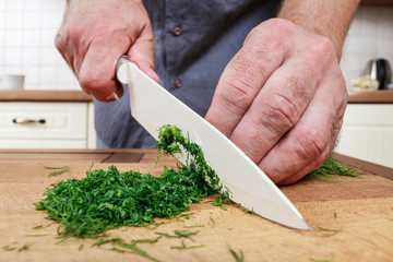 Man chops dill in the kitchen.