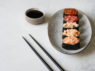 Variety gunkans with salmon, shrimp, tuna, mussels, red caviar on an oval ceramic plate