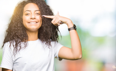 Young beautiful girl with curly hair wearing casual white t-shirt Pointing with hand finger to face and nose, smiling cheerful