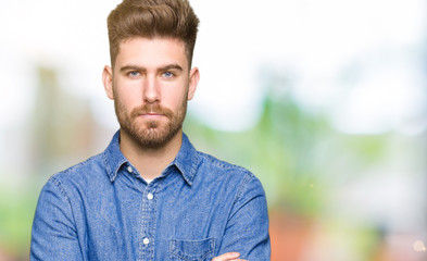 Fototapeta premium Young handsome blond man wearing casual denim shirt skeptic and nervous, disapproving expression on face with crossed arms. Negative person.