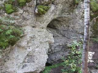 Rocky entrance to the cave, located in the densely growing Ural forest.