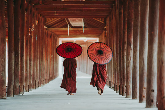 Tear view of two Buddhist monks walking with parasols, Bagan, Myanmar