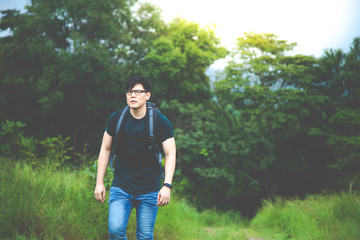 Young backpacker with backpack traveling along at forest. Tourist hiking in jungle forest.