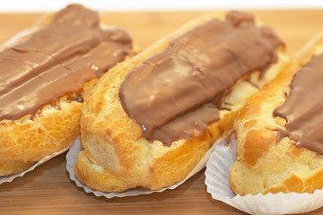 Three home made cream puffs against a white background