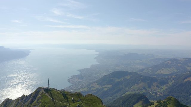 Aerial shot overflying Les Rochers de Naye high summit with view over Lake Leman in the distance. Camera tilting down to reveal Montreux area far below. Switzerland