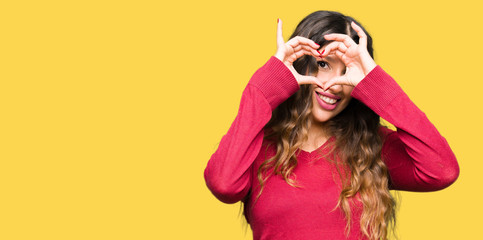 Young beautiful woman wearing red sweater Doing heart shape with hand and fingers smiling looking through sign