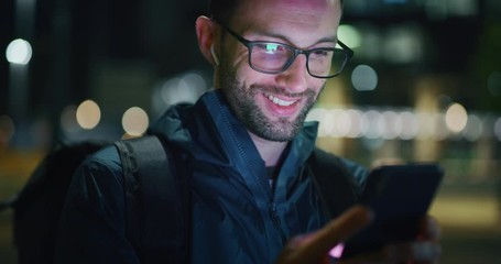 Slow motion close up of young man is using mobile phone in a center of the city by night. - Powered by Adobe