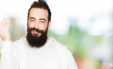 Young hipster man with long hair and beard wearing sporty sweatshirt Doing Italian gesture with hand and fingers confident expression