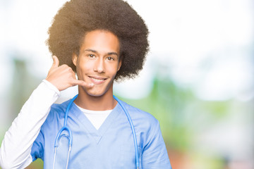 Young african american doctor man with afro hair smiling doing phone gesture with hand and fingers like talking on the telephone. Communicating concepts.