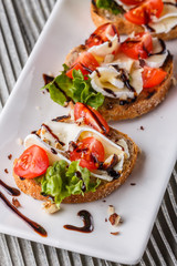 Bruschetta with tomatoes, lettuce, camambert, balsamic vinegar