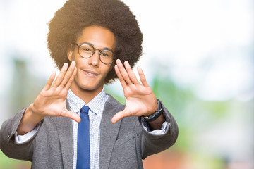 Young african american business man with afro hair wearing glasses Smiling doing frame using hands palms and fingers, camera perspective